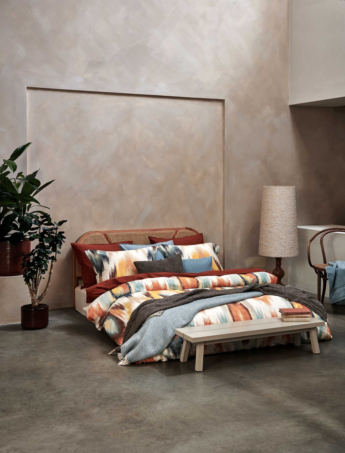 Tribal multi dekbedovertrek heeft een patroon van zigzaglijnen met ruiten ogen erin die verlopen lijken te zijn in verschillende tinten blauw, oranje, geel en beige op een offwhite achtergrond. De achterkant van het dekbedovertrek is effen offwhite.